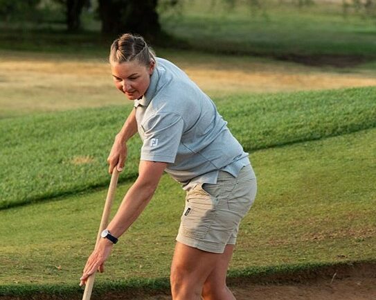 Women in turf program, image of a female groundskeeper holding a rake in a golf course