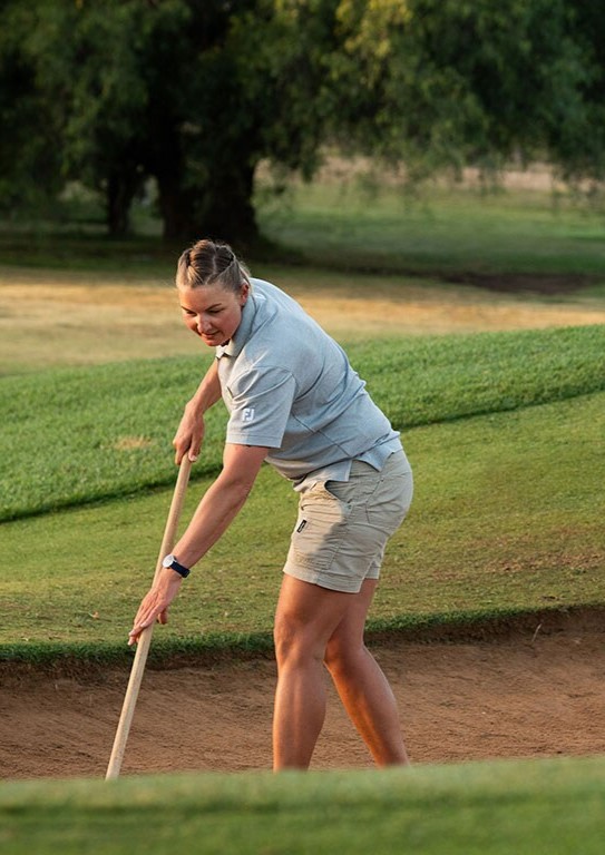 Women in turf program, image of a female groundskeeper holding a rake in a golf course